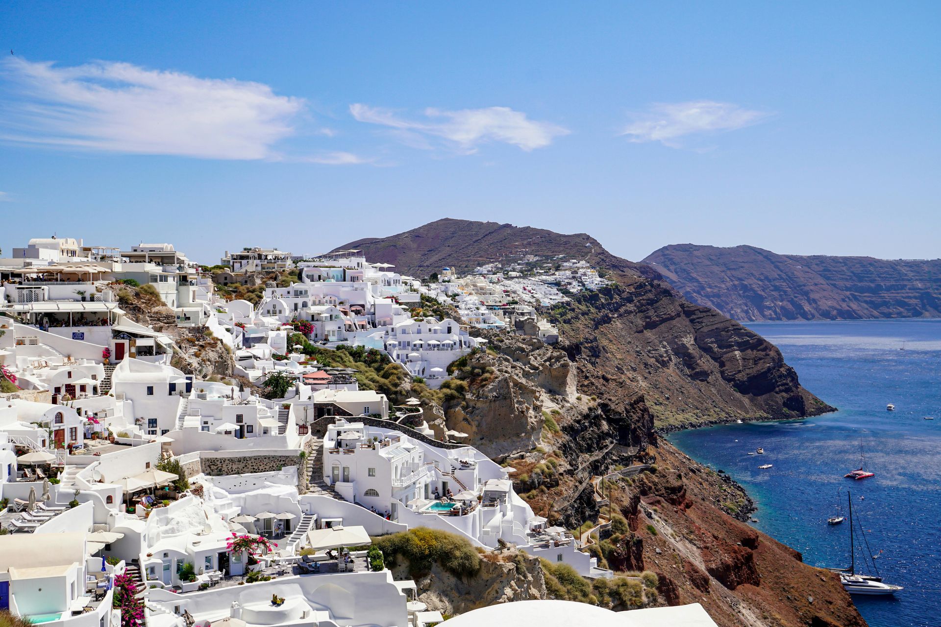 A breathtaking view of Santorini’s blue-domed churches and whitewashed houses glowing under the soft morning light, with the Aegean Sea stretching endlessly in the background.