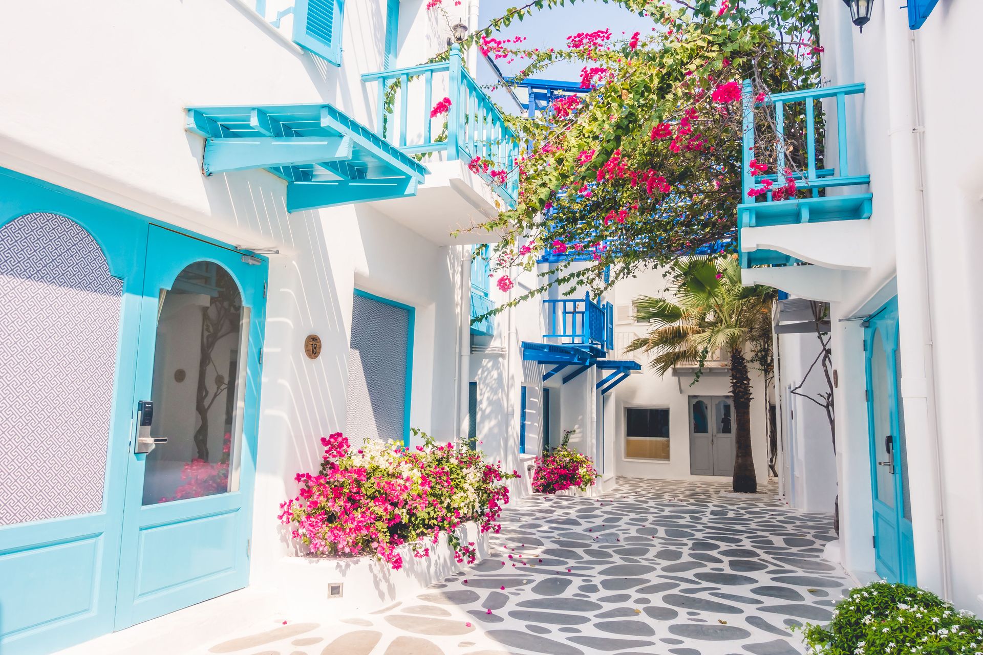 A quaint alleyway in Santorini lined with whitewashed buildings, blue doors, and a charming bookstore tucked into a corner.