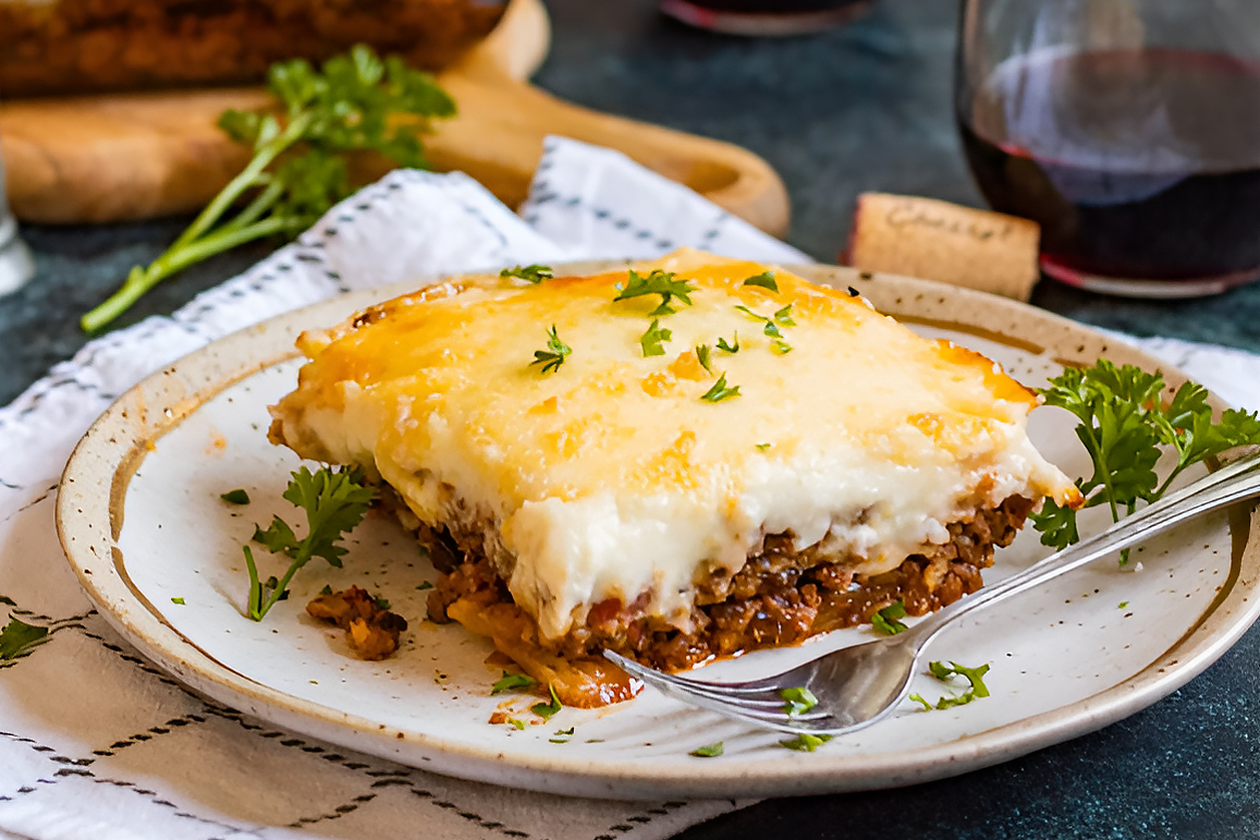 A candlelit Greek taverna in Santorini with a plate of moussaka and a glass of Retsina wine on a wooden table.