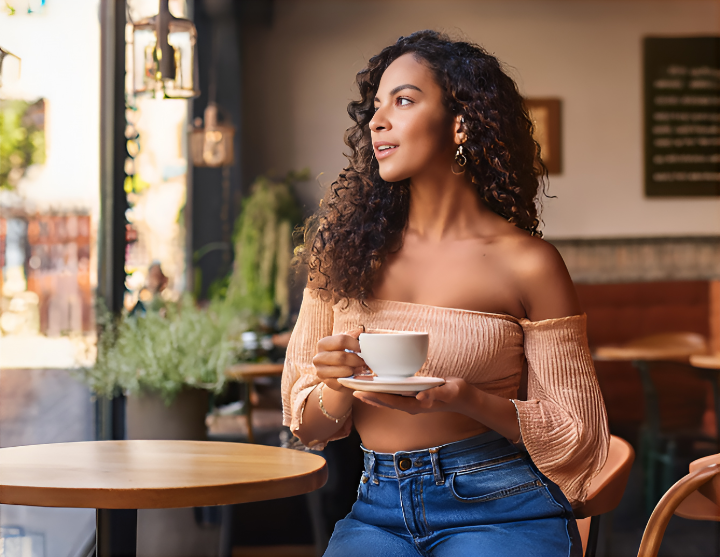 A casual café scene with a fashionable woman sipping coffee in an off-shoulder top and stylish jeans - the pink story