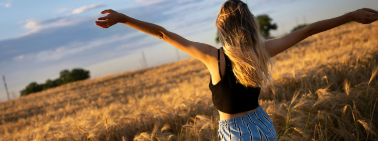 Seraphina Vale, Co-Founder of The Pink Story, embracing freedom and creativity in a golden wheat field.