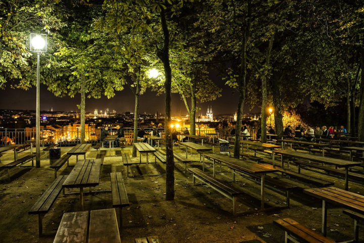 The city lights shimmer across the river at Letná Park.